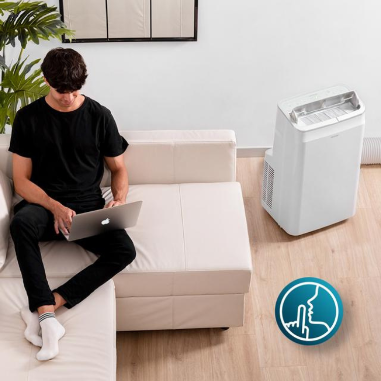 Cecotec ForceClima 12800 Soundless portable air conditioner, white, 12000BTU, next to a couch with a man using a laptop.