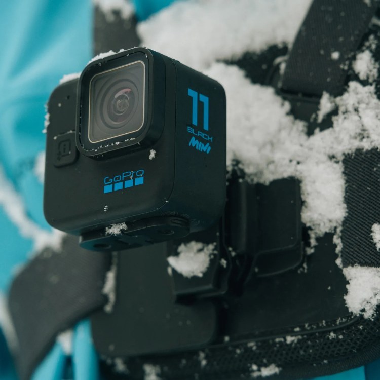 GoPro Hero11 Black Mini camera on black chest mount with snow.