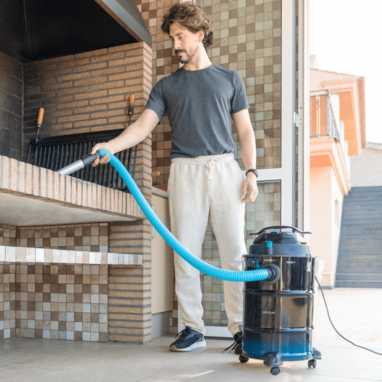 Aspirador de cinzas Cecotec Conga Ash 6000 EasyGo Home XL preto e azul, com homem a utilizar numa área exterior.