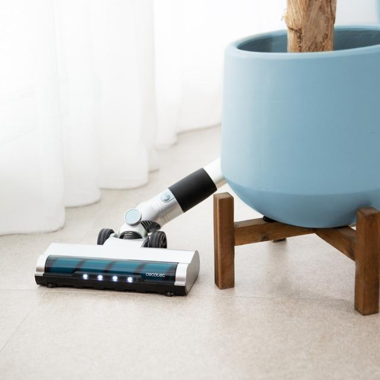 Cecotec Scoba 2100 Jalisco upright vacuum cleaner, white and black, on beige floor next to blue pot.