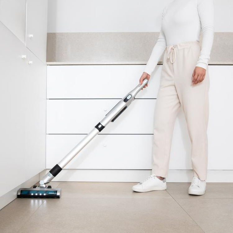 Cecotec Scoba 2100 Jalisco upright vacuum cleaner, silver and black, with blue lights, being used on beige tiles.