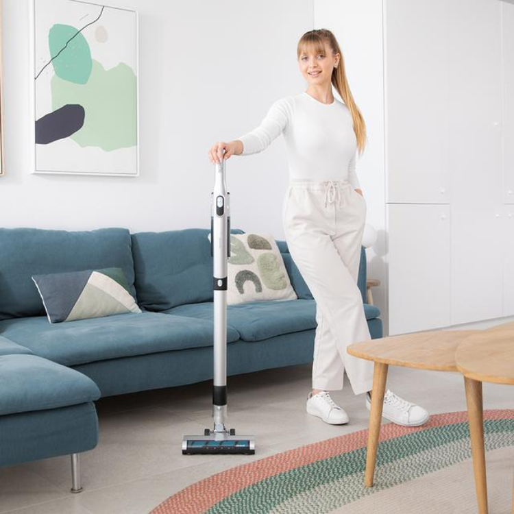 Cecotec Scoba 2100 Jalisco upright vacuum cleaner, silver and black, with woman using it on a rug in a living room.