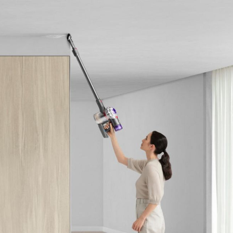 Dyson V8 silver and nickel vertical vacuum cleaner with woman using it.