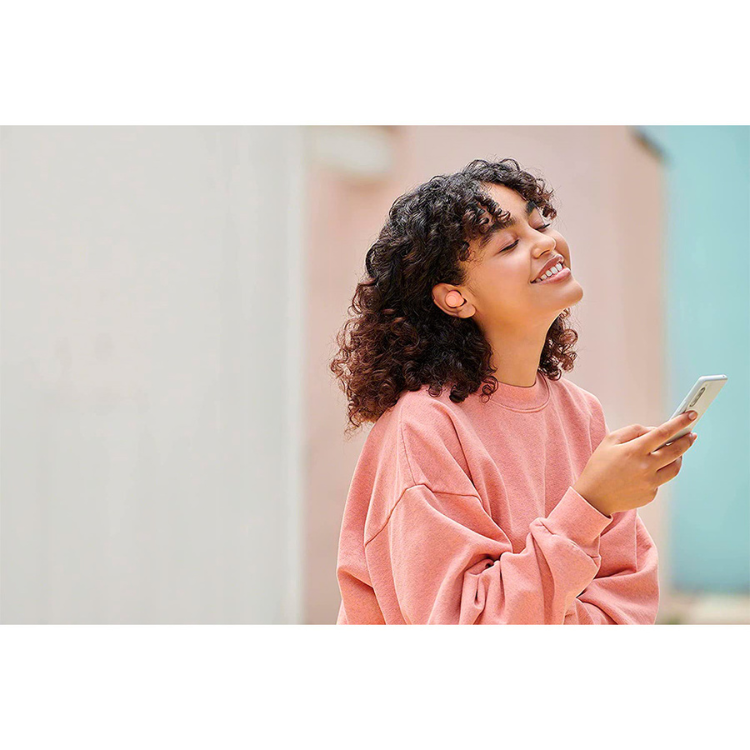 Mulher com auriculares Sony WF-C500 cor laranja a ouvir música com telemóvel.
