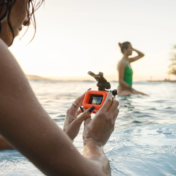 Orange GoPro Floaty for HERO, in water with woman holding it.