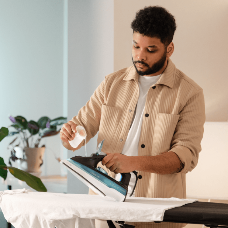 Cecotec IronHero 2600 Force steam iron, blue and black, on ironing board.