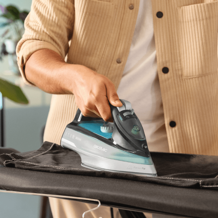 Cecotec IronHero 2600 Force steam iron, silver and teal, on ironing board.