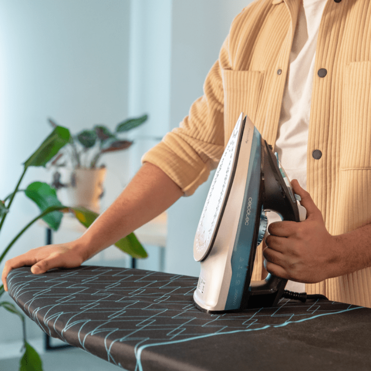 Cecotec IronHero 2600 Force steam iron, white and blue, on ironing board.