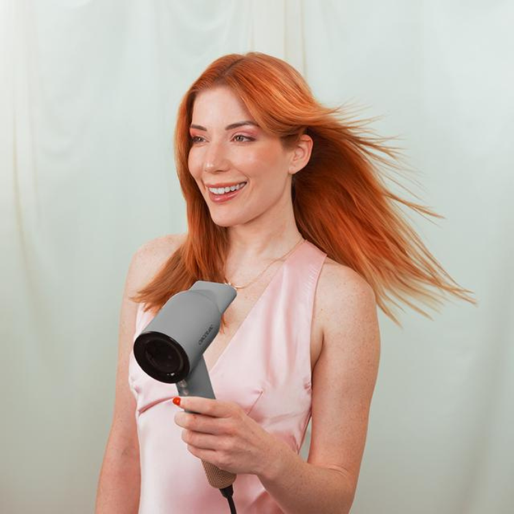 Woman with red hair holding gray Cecotec hair dryer.