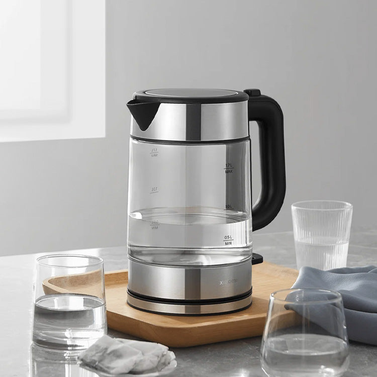 Xiaomi Mi Electric Glass Kettle, silver and black, on wooden board with glasses.