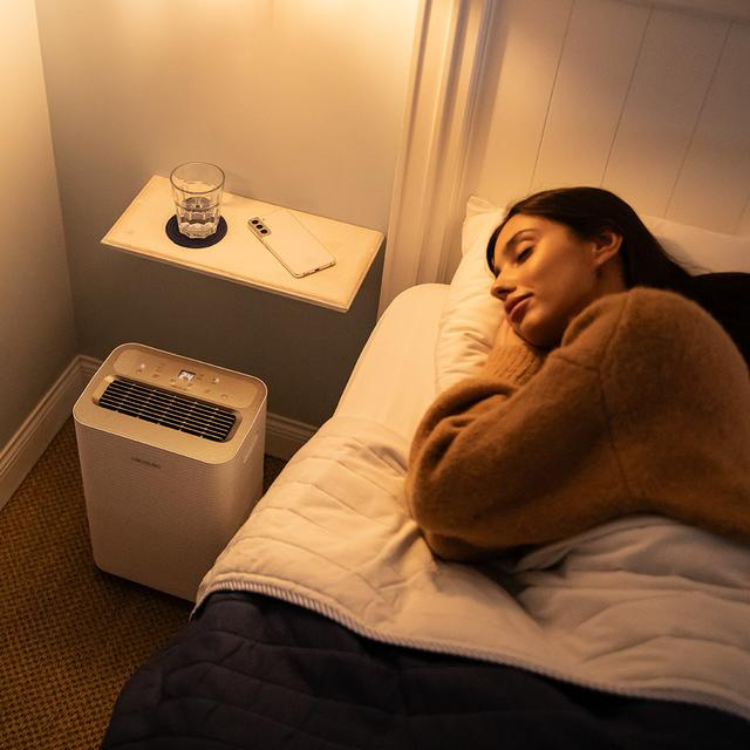 Cecotec BigDry dehumidifier next to bed with sleeping woman.