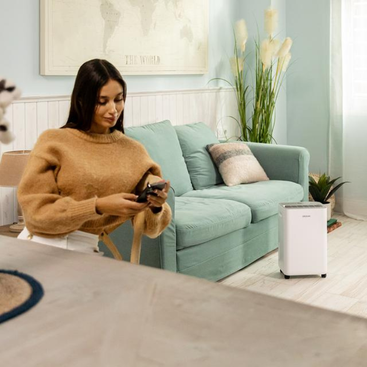 Cecotec BigDry 10000 Expert dehumidifier, white, next to sofa.