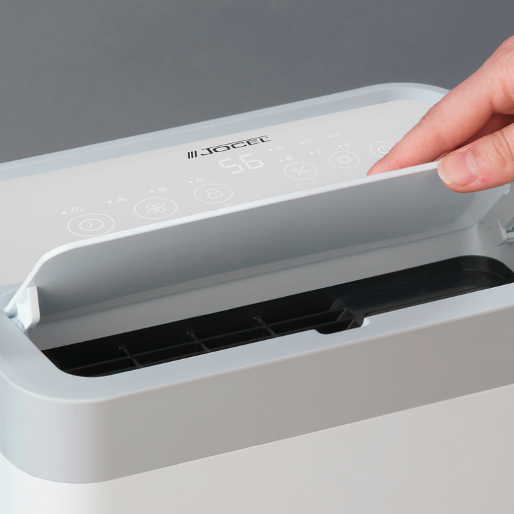 White Jocel dehumidifier with control panel and finger pressing button.