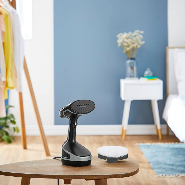 Rowenta vertical steam iron, black and silver, on a wooden table.