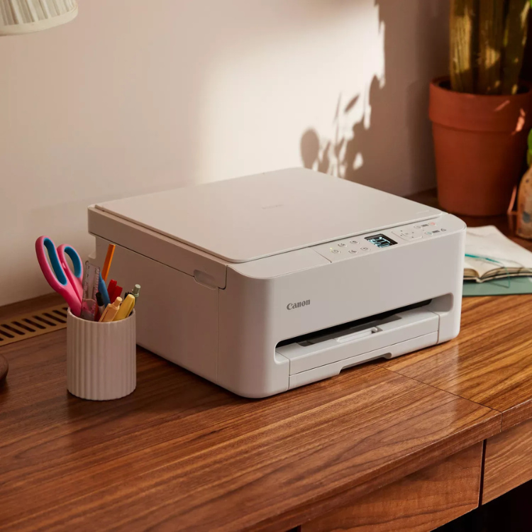 Canon Pixma TS7550i white inkjet multifunction printer on wooden desk.