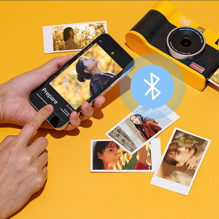 Yellow Kodak Mini Shot 2 Era MS200 instant camera, black and yellow, with photos and phone.