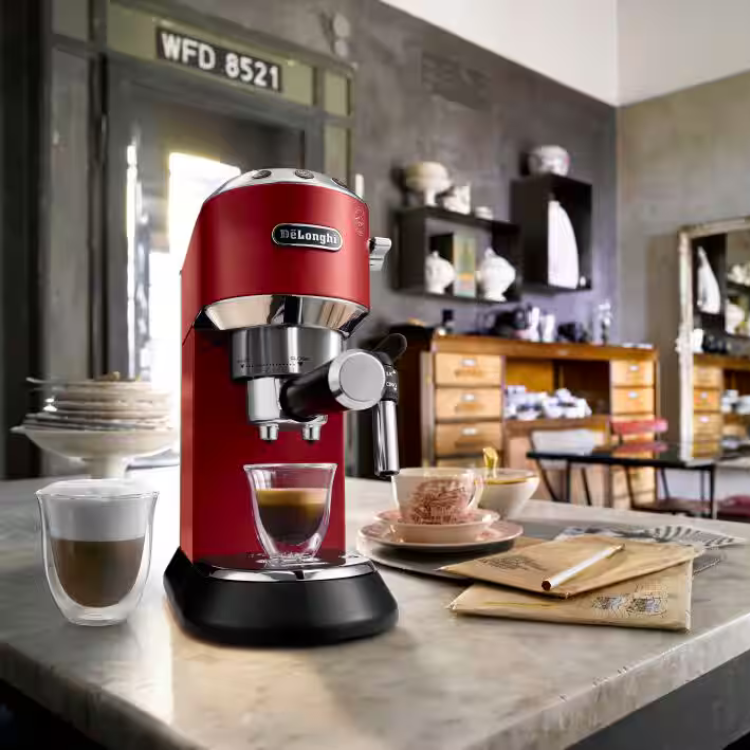Red De'Longhi manual espresso machine on countertop with coffee cups.