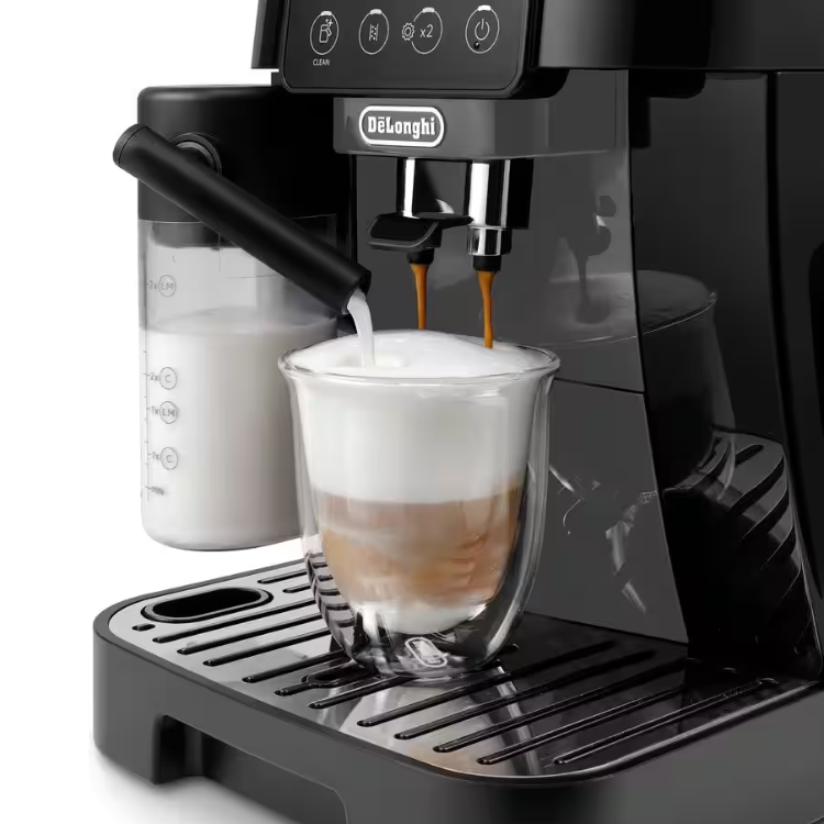 Black DeLonghi Magnifica Start LatteCrema coffee machine dispensing coffee and milk into glass.