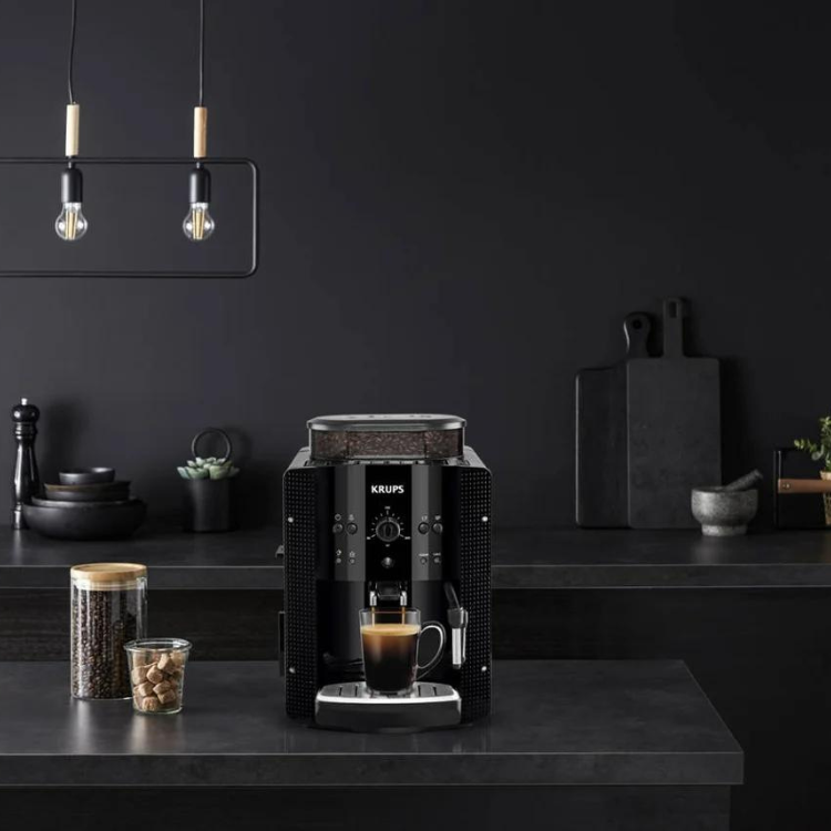 Black Krups Roma fully automatic espresso machine on a counter with coffee beans and a cup of coffee.
