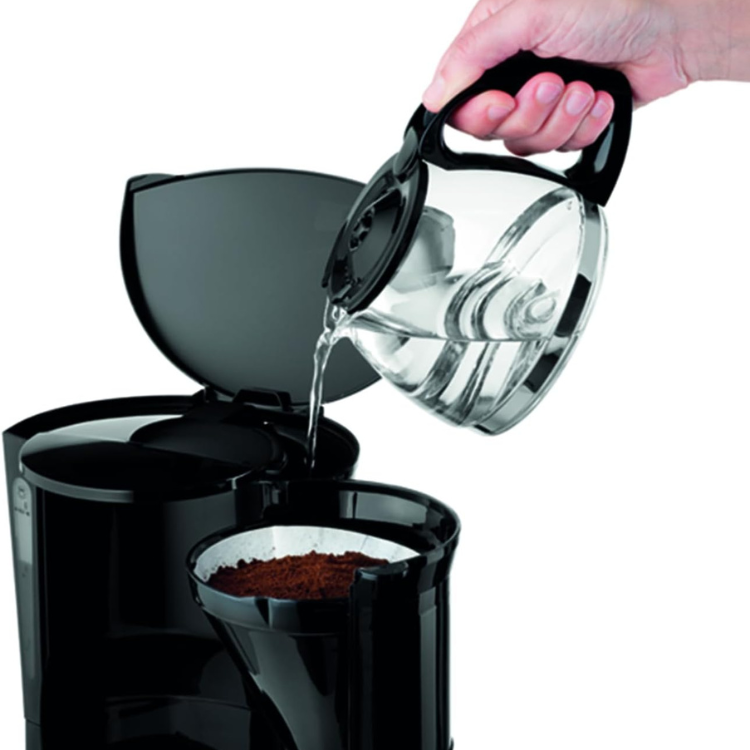 Black Moulinex coffee filter machine with glass carafe and ground coffee, water being poured.