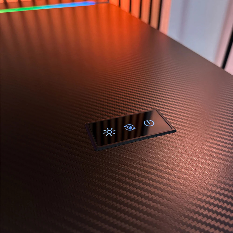 Electric desk control panel with sun, eye and power buttons on carbon fiber surface.
