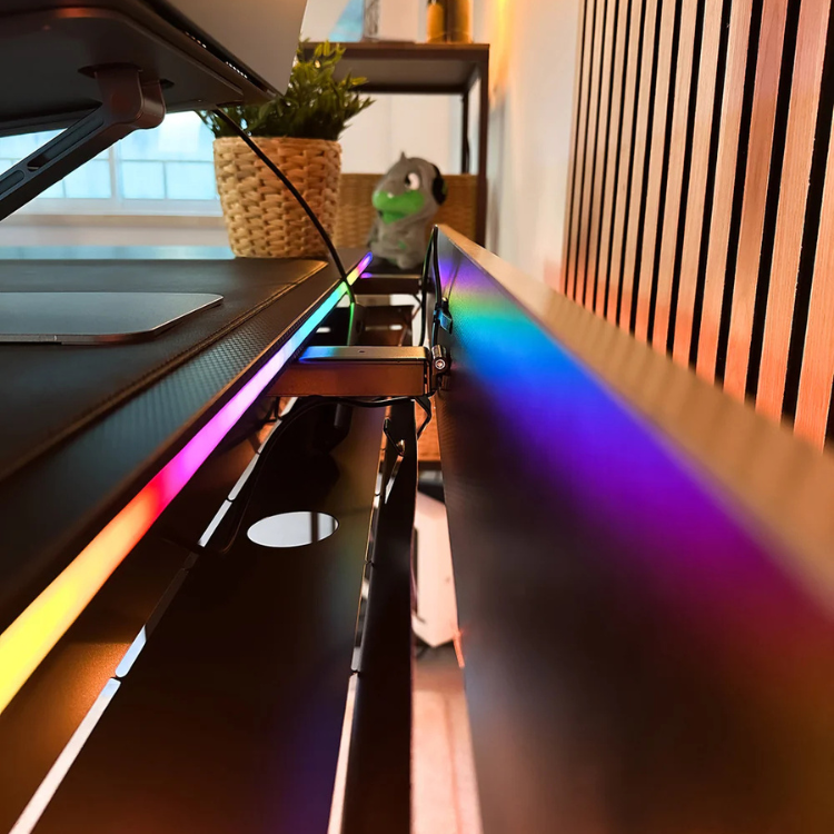 Electric gaming desk with RGB rainbow lighting, black surface, and ergonomic design, 140cm wide.