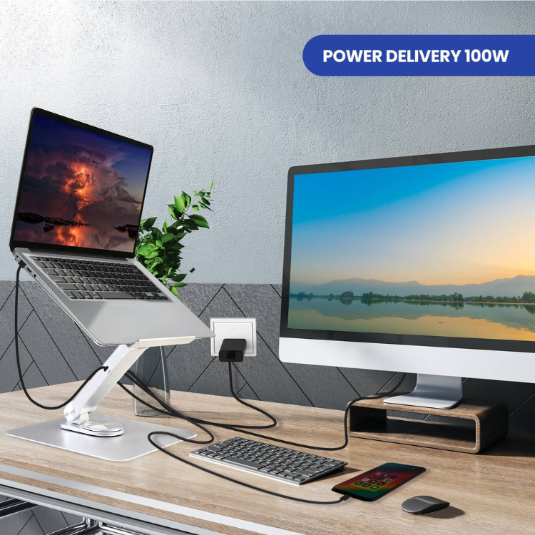 Ewent aluminium laptop stand with 360° rotation and USB hub on wooden desk with laptop, monitor, keyboard, mouse and phone.