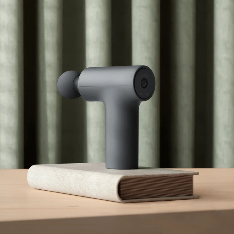 Xiaomi Mini 2 massage gun, gray, on a book.