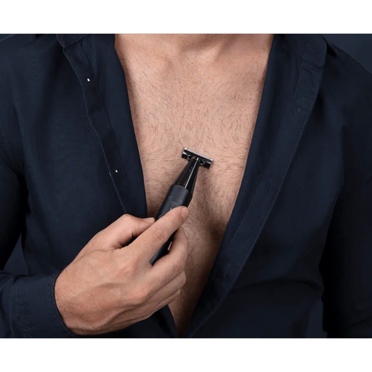Black Xiaomi Uniblade Trimmer in man's hand, shaving chest hair.
